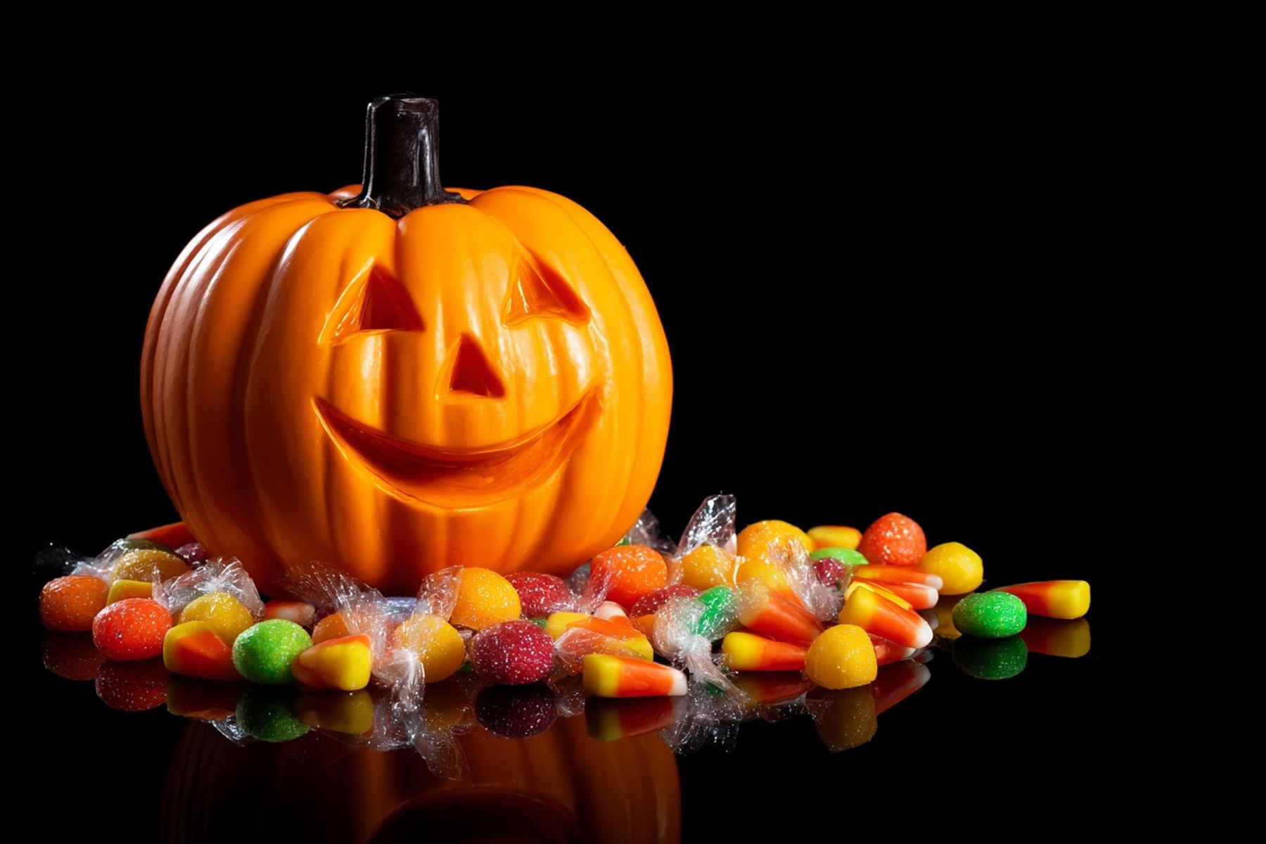 Abóbora de Halloween e doces coloridos sobre fundo preto